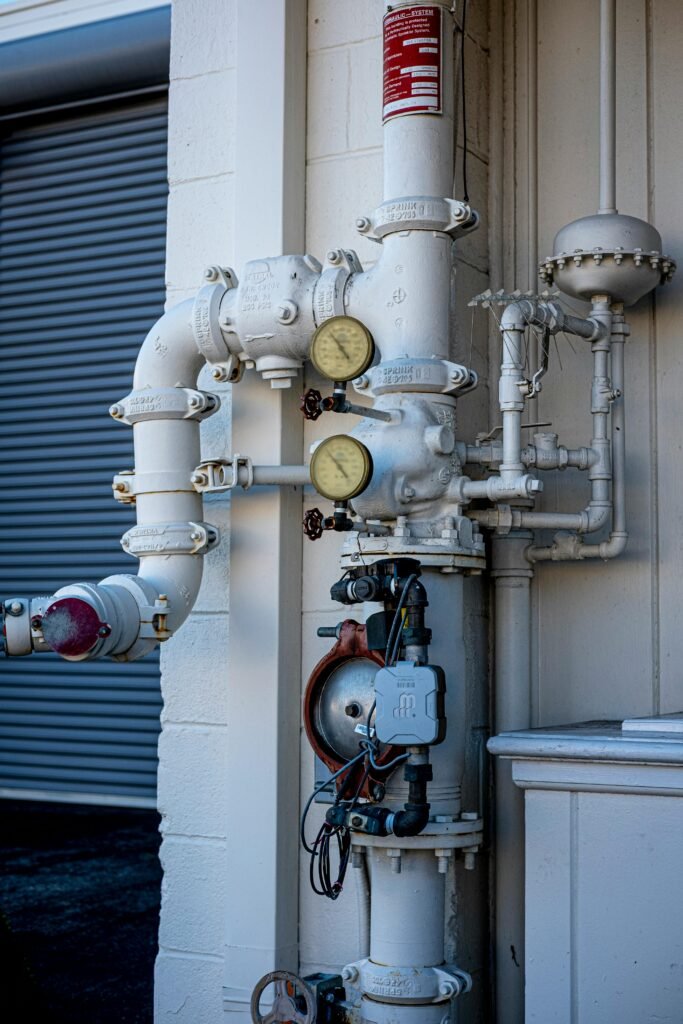Close-up shot of an industrial pipe system featuring pressure gauges and valves outdoors.