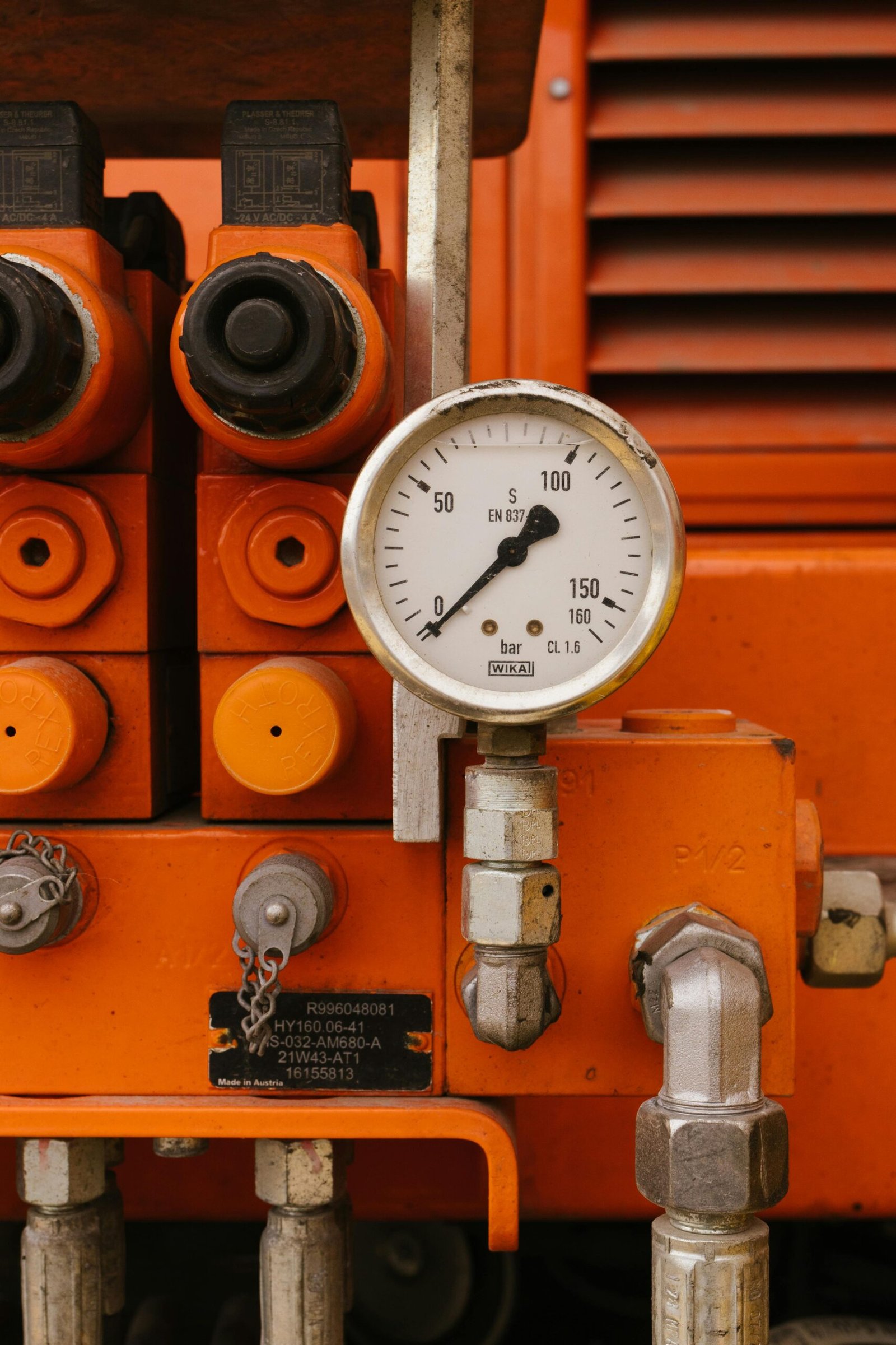 Detailed view of a pressure gauge on orange industrial machinery, showcasing engineering equipment.