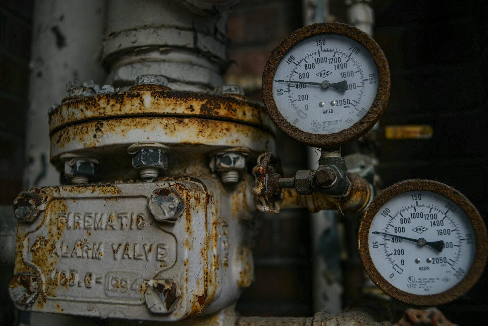 Close-up of an aged and rusted pressure valve with gauges showing readings.